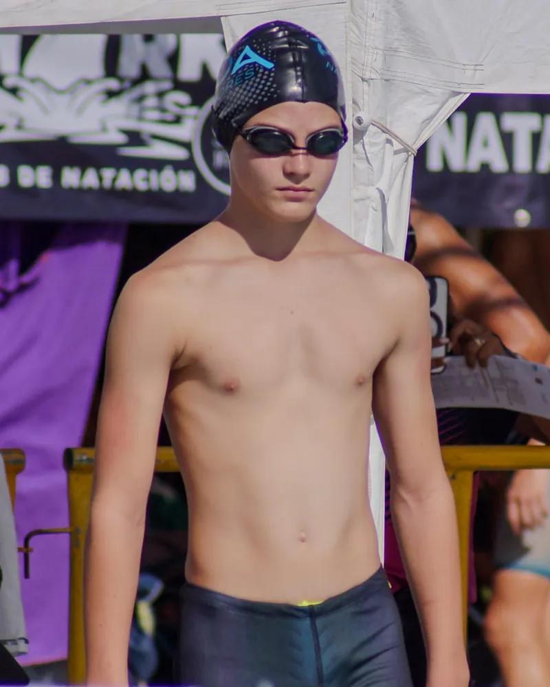 Nadador con gorra de PROA Nadadores esperando su turno bajo la carpa de una competencia de natación