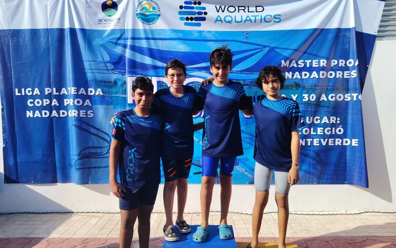 Cuatro niños del equipo PROA Nadadores con la playera del club posan en el podio de la Copa PROA en Cancún